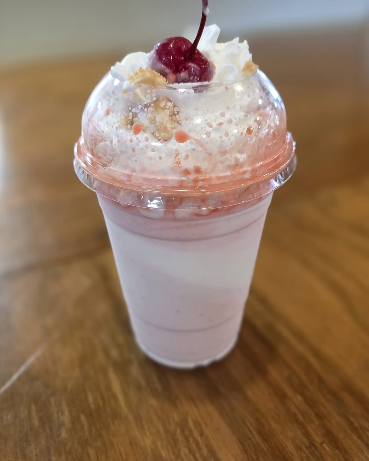 A milkshake in a dome-lid cup with whipped cream, crumb topping, and a cherry at The Coney Island in Pottsville, PA.