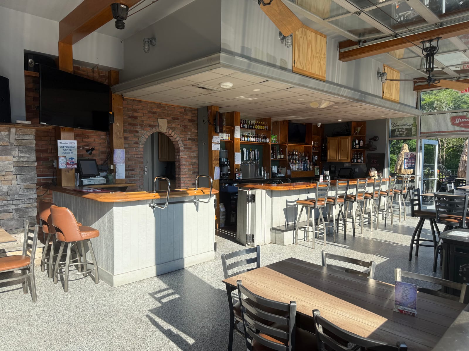 Inside the four-season patio at The Coney Island in Pottsville, PA — the patio's own bar, tables, and roll-up glass doors.
